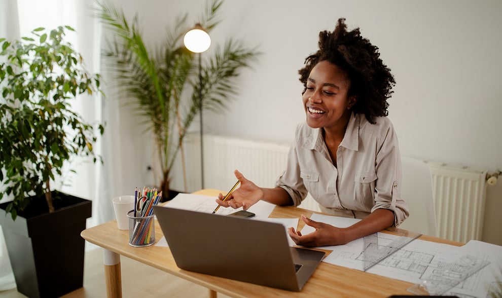 Woman sat at a desk smiling at her computer screen