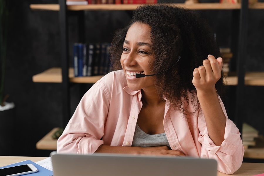 Woman sat smiling at laptop while on a call